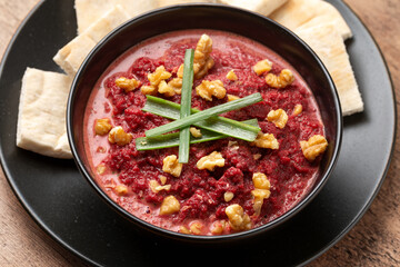 healthy homemade beetroot dip sauce hummus, in rustic clay bowl served with pita bread, walnuts and parsley