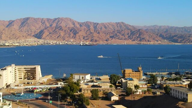 Aerial Shot Of Nautical Vessels Moving In Sea By Mountains, Drone Flying On Sunny Day - Eilat, Israel