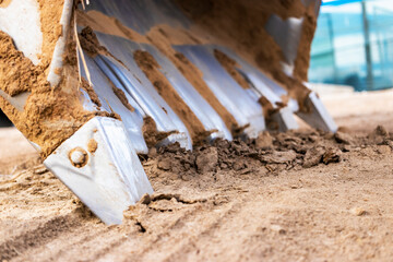 Excavator bucket close-up on the background of a construction site. Heavy earthmoving equipment. Soil development. © Anoo