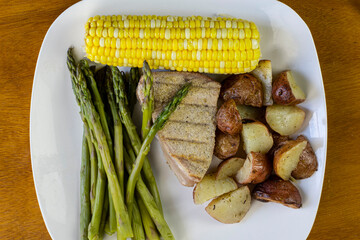tuna  steak  with asparagus and corn served with red roasted potatoes