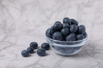 Blueberries in a ceramic bowl on a light textured background. Ripe and fresh blueberries. Vitamins. Healthy food. Juicy berry.Copy space.Place for text