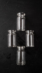 formación de cuatro botes de vidrio pequeños vacíos, sobre fondo de madera negra pintada 