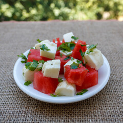 Plate of Cypriot traditional halloumi cheese and watermelon salad on garden table