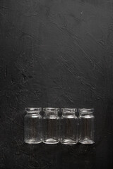 formación de botellitas de vidrio vacías sobre fondo negro de madera con textura