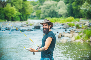 Hipster bearded man catching trout fish. Fisherman caught a fish. Man fishing on river.