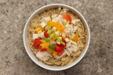 homemade ramen noodles with vegetables and chicken in white ceramic bowl with neutral background