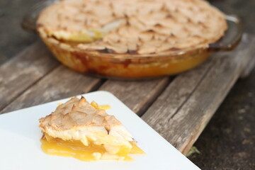 Lemon Meringue Pie Slice on white plate on grey wooden background