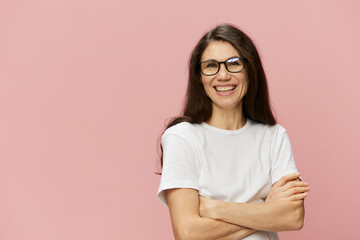 portrait of a cute, attractive brunette in a white tank top on a pink background, with a pleasant smile, standing in glasses for vision