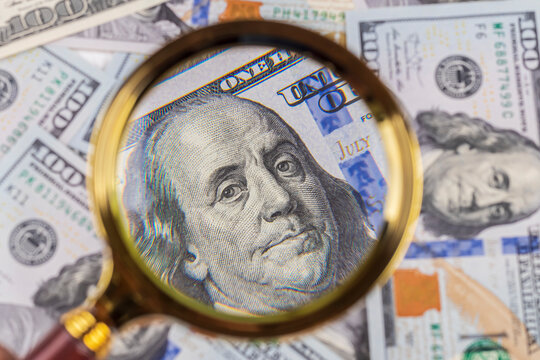 one hundred dollars. a magnifying glass in a gold frame. close-up