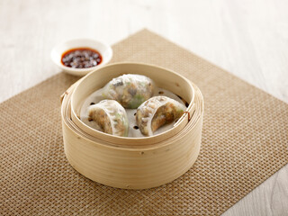 Steamed Dumpling with Preserved Olive Vegetable served in a wooden bowl isolated on mat side view...