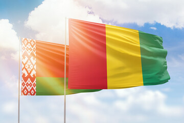 Sunny blue sky and flags of guinea and belarus