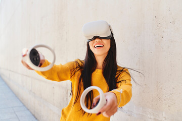 Portrait of Asian woman playing in metaverse using VR set outdoors in the city