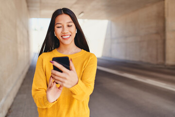 Smiling Asian woman using smartphone in the city