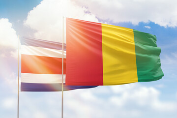 Sunny blue sky and flags of guinea and costa rica