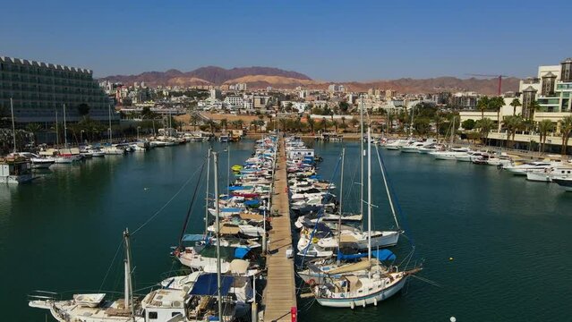 Aerial Tilt Down Shot Of Jetty Amidst Nautical Vessels At Harbor, Drone Flying Upwards Over Red Sea In City - Eilat, Israel