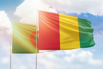 Sunny blue sky and flags of guinea and algeria