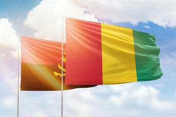 Sunny blue sky and flags of guinea and angola