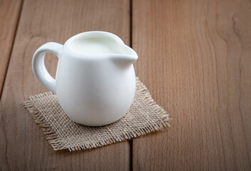 White jug with milk on a wooden rustic background