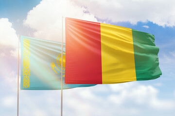 Sunny blue sky and flags of guinea and kazakhstan