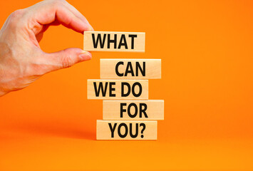 Support symbol. Concept words What can we do for you on wooden blocks on a beautiful orange table orange background. Businessman hand. Business motivational and support concept.