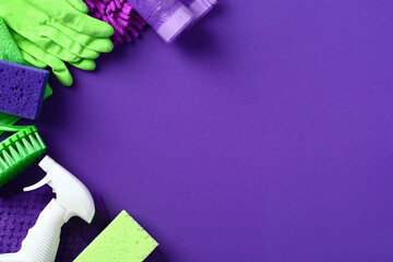 Flat lay cleaning products and supplies on purple background. House cleaning service and housekeeping concept.