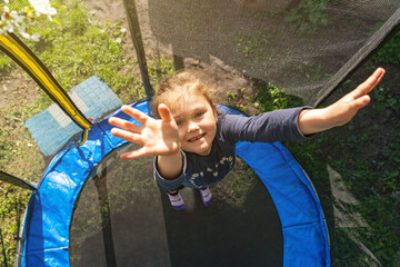 Little girl jumping on a trampoline on a summer day