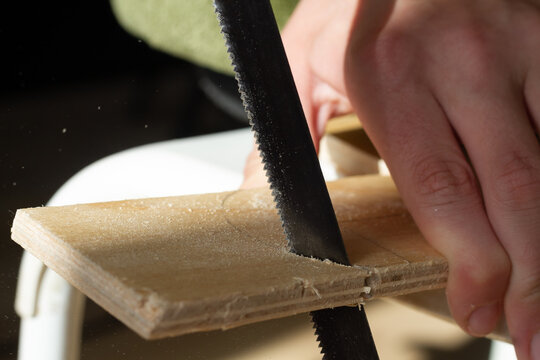 Sawing wooden plywood with a jigsaw, sawdust flying from the saw to the sides