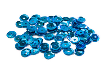 Bright beautiful blue sparkles sequins scattered on white textured background, close up macro