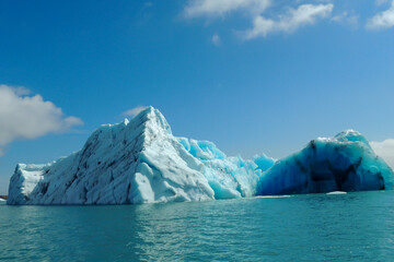 Fototapeta na wymiar Bright clear blue iceberg floating in the Jokulsarlon lake blue cold water in Iceland 15