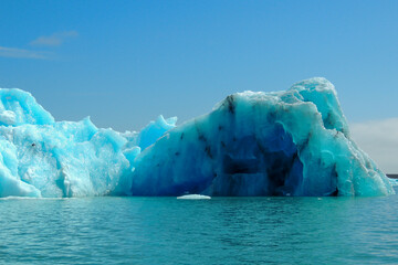 Fototapeta na wymiar Bright clear blue iceberg floating in the Jokulsarlon lake blue cold water in Iceland 23