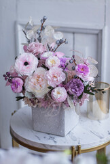 Light gray concrete planter with flowers. Gently pink anemones, pink roses and cream peonies with eucalyptus. Composition on a marble table. Floristics preserved flowers.