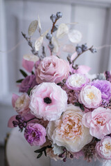 Light gray concrete planter with flowers. Gently pink anemones, pink roses and cream peonies with eucalyptus. Composition on a marble table. Floristics preserved flowers.