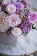 Light gray concrete planter with flowers. Gently pink anemones, pink roses and cream peonies with eucalyptus. Composition on a marble table. Floristics preserved flowers.