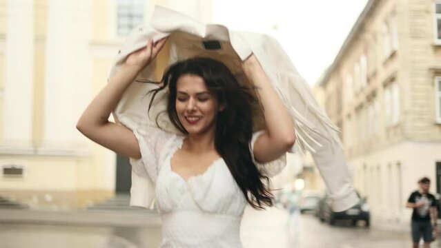 Beautiful Brunette Woman Running Down The Street In The Rain Without An Umbrella Hiding Behind A Jacket.