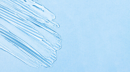 Transparent hyaluronic acid gel on a blue background with copy space. Banner with cosmetic texture for body care, flat lay.