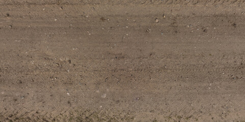 panorama of surface from above of gravel road with car tire tracks