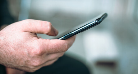 Close-up, a man uses a smartphone while browsing the Internet, searching for data on the network, or browsing social networks.