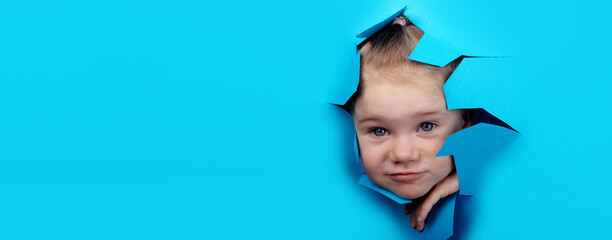little girl looking through a hole in blue paper, panoramic layout