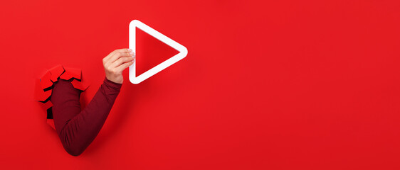 hand holding 3d media play button over red background, panoramic layout