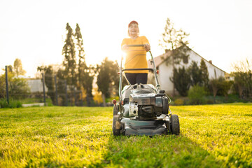 Woman mowing with lawn mower in the garden, gardening concept