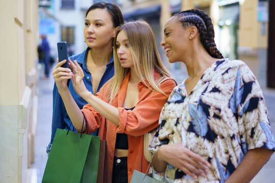 Multiracial women taking photo of showcase on smartphone