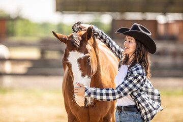 Young woman brushes her paint horse outdoors on a farm