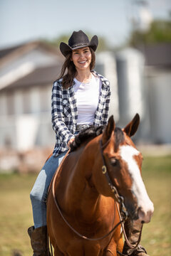 Beautiful smiling girl riding a paint horse, wearing a black cowboy hat