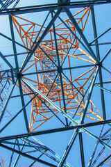Close-up view of an electric tower with a beautiful blue sky background. Industrial engineering concept. Iron structure for high-voltage electrical engineering.