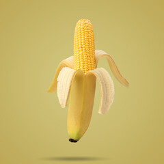 Cob of corn in the peel of banana on yellow background. Food creative concept. Photo manipulation...