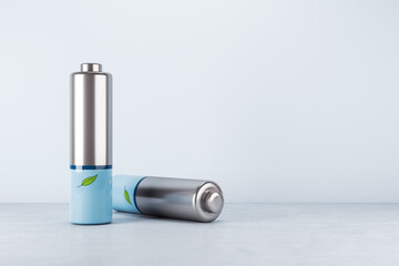 Green energy and eco technology concept with silver and blue batteries and green leaf on concrete surface and blank light blue wall with place for your logo or text background. 3D rendering, mockup