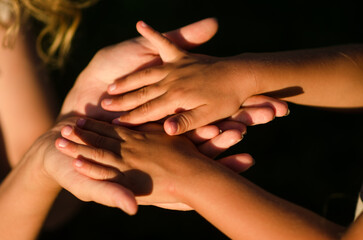 Mother holding a hand of his son in summer day outdoors. Sunlight at sunset