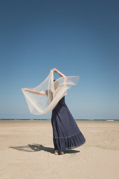 woman on the beach in classic blue dress dancing 
