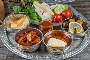 Healthy traditional Turkish breakfast, scrambled eggs with sausage ,cheeses ,olives ,tomatoes ,cucumbers.etc. served on a tray with tea