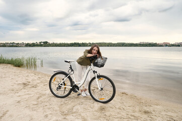 Fototapeta premium A portrait of a young beautiful girl with a bicycle on the river band